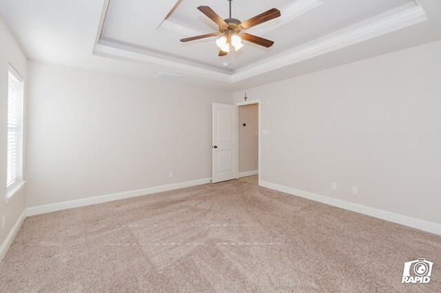 empty room featuring crown molding, baseboards, light colored carpet, a tray ceiling, and a ceiling fan