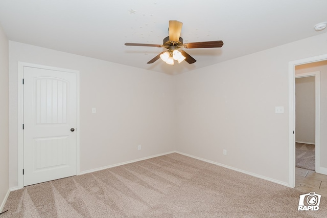 empty room featuring light colored carpet, baseboards, and a ceiling fan