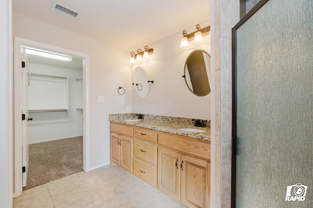 bathroom featuring tile patterned flooring, visible vents, double vanity, and a sink