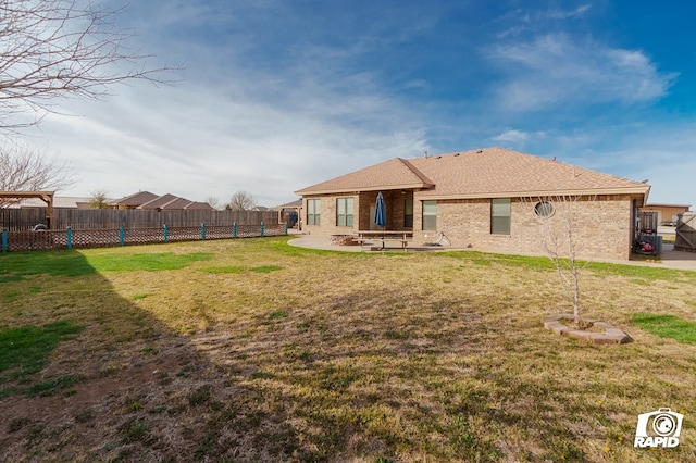 back of house with a patio, a lawn, a fenced backyard, and brick siding