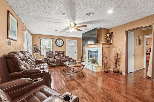3804 Cedar Spg, Midland, TX 79703 - living room with a tiled fireplace, ceiling fan, wood finished floors, a textured ceiling, and a textured wall