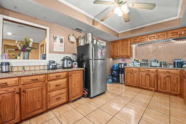 3804 Cedar Spg, Midland, TX 79703 - kitchen featuring a textured ceiling, freestanding refrigerator, brown cabinets, light tile patterned flooring, and a ceiling fan