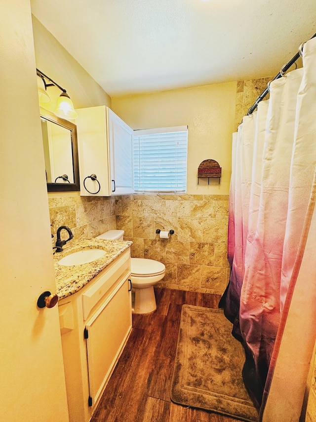 bathroom with hardwood / wood-style floors, vanity, toilet, and tile walls