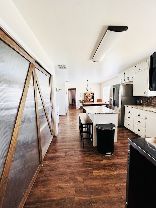 kitchen with a center island, white cabinetry, dark wood-type flooring, and backsplash