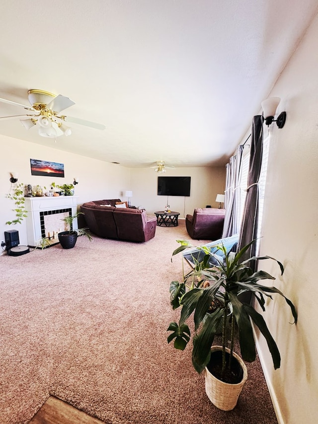 living room featuring ceiling fan, carpet floors, and a tiled fireplace