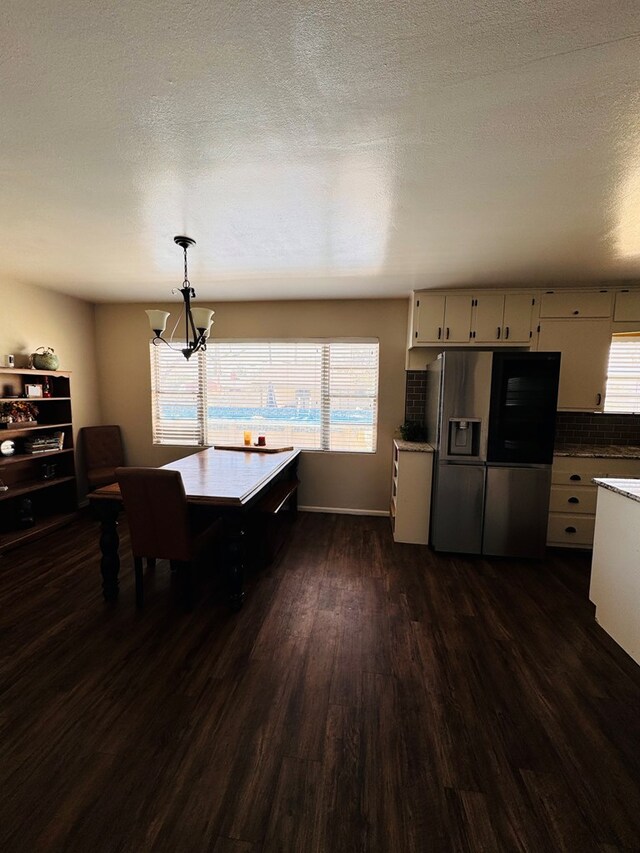 dining space featuring a textured ceiling, dark hardwood / wood-style floors, and an inviting chandelier