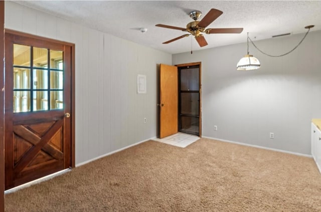 carpeted spare room featuring ceiling fan and a textured ceiling