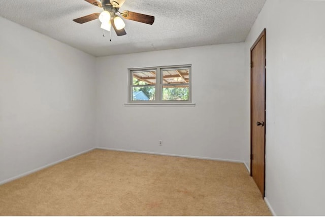 empty room featuring ceiling fan, a textured ceiling, and light carpet