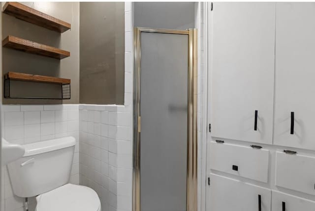 bathroom featuring toilet, tile walls, and an enclosed shower