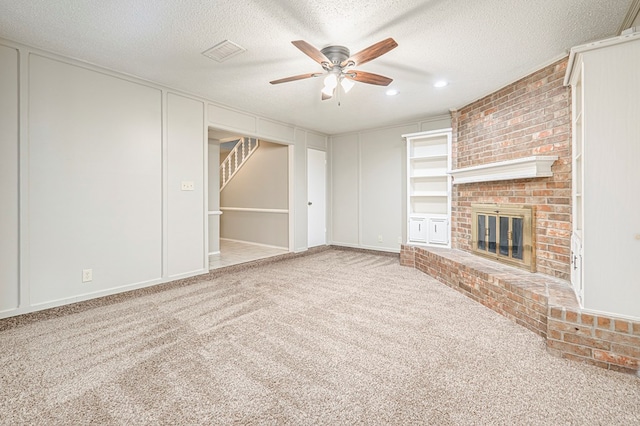 3205 Dentcrest Dr Unit B, Midland, TX 79707 - unfurnished living room with ceiling fan, carpet, a fireplace, a textured ceiling, and a decorative wall