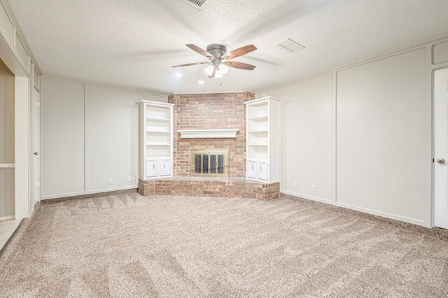 3205 Dentcrest Dr Unit B, Midland, TX 79707 - unfurnished living room featuring a ceiling fan, a textured ceiling, carpet, a brick fireplace, and a decorative wall