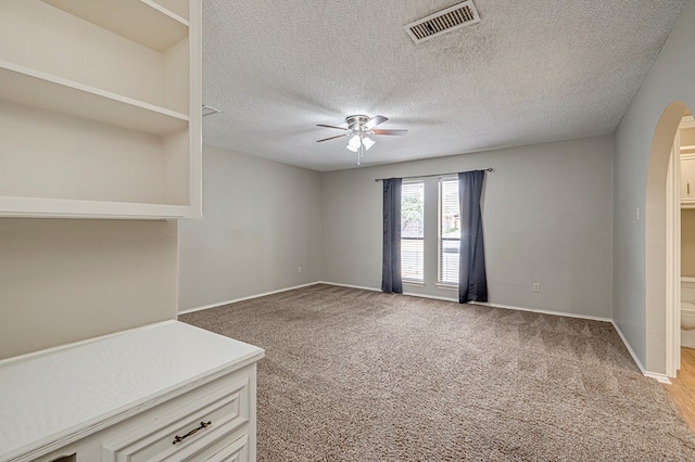3205 Dentcrest Dr Unit B, Midland, TX 79707 - unfurnished living room with a ceiling fan, arched walkways, a textured ceiling, baseboards, and light colored carpet