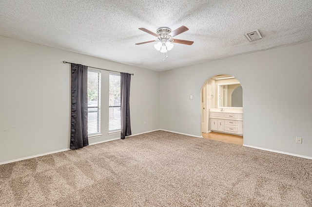 3205 Dentcrest Dr Unit B, Midland, TX 79707 - spare room with a ceiling fan, light colored carpet, arched walkways, baseboards, and a textured ceiling