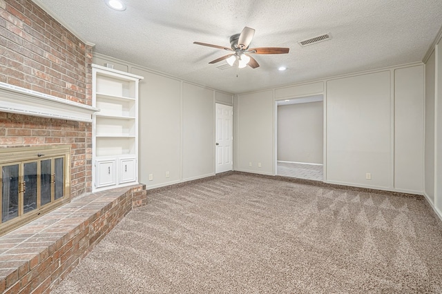 3205 Dentcrest Dr Unit B, Midland, TX 79707 - unfurnished living room featuring a ceiling fan, a decorative wall, a textured ceiling, carpet flooring, and a fireplace