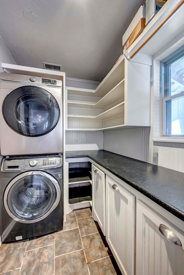 1002 Boyd Ave, Midland, TX 79705 - washroom with visible vents, stacked washer and clothes dryer, and cabinet space