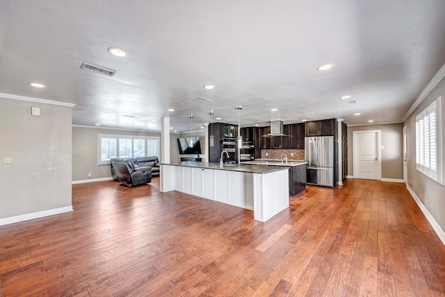 1002 Boyd Ave, Midland, TX 79705 - kitchen with dark brown cabinetry, freestanding refrigerator, open floor plan, wall chimney range hood, and visible vents