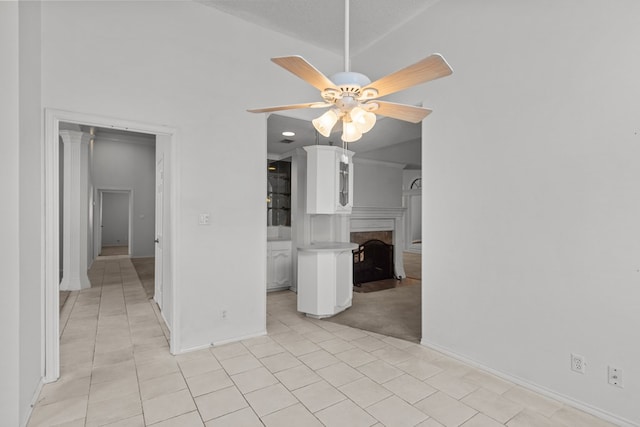 interior space featuring a fireplace, light tile patterned floors, a ceiling fan, and baseboards