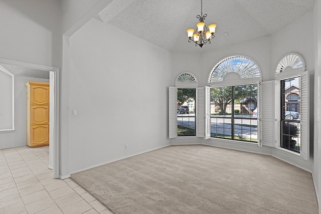 spare room with baseboards, light tile patterned flooring, a textured ceiling, a notable chandelier, and light colored carpet