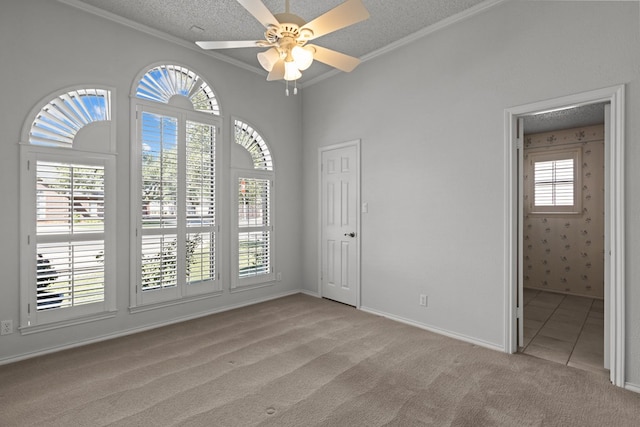 empty room featuring light colored carpet, ornamental molding, a ceiling fan, and a textured ceiling