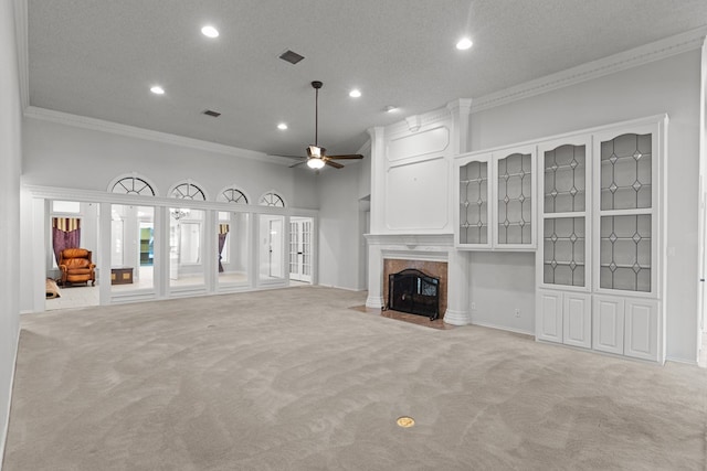 unfurnished living room featuring a ceiling fan, visible vents, a high end fireplace, crown molding, and light colored carpet