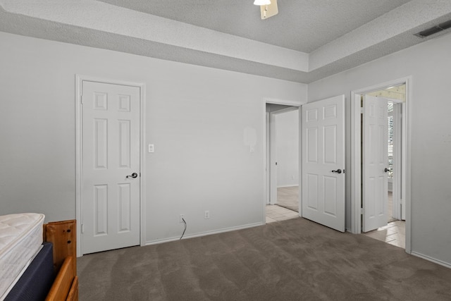 unfurnished bedroom with visible vents, a textured ceiling, baseboards, and carpet floors