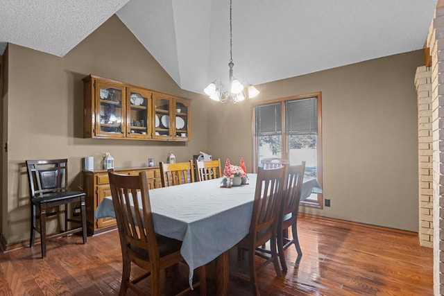 dining room with dark wood-type flooring, lofted ceiling, and a chandelier