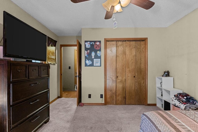 carpeted bedroom featuring ceiling fan, a closet, and a textured ceiling