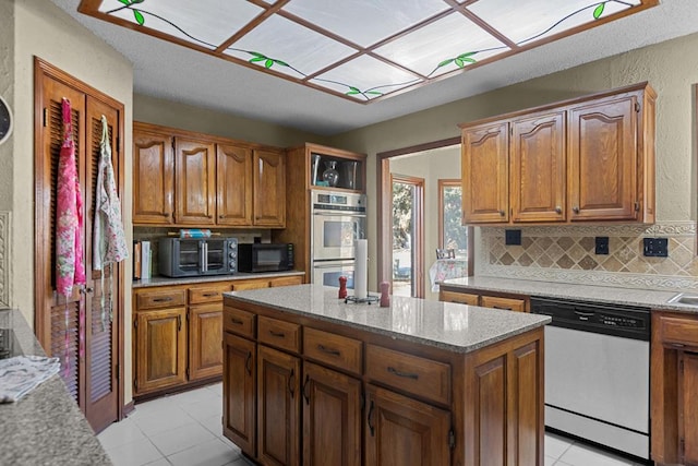 kitchen featuring tasteful backsplash, light tile patterned floors, stainless steel appliances, and a center island