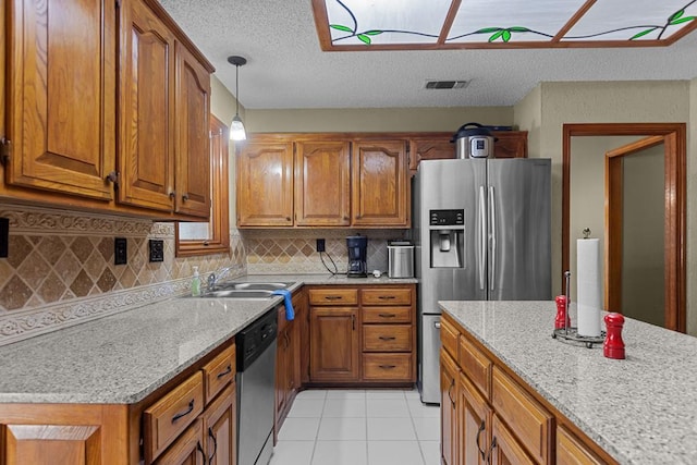 kitchen with stainless steel appliances, light stone countertops, and sink