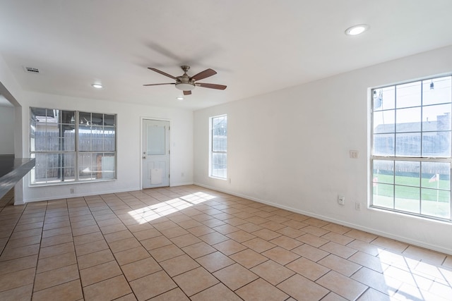 empty room with light tile patterned flooring, visible vents, baseboards, and a ceiling fan