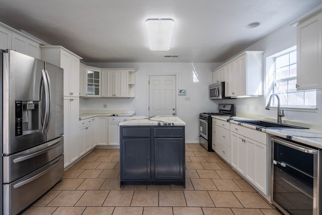 kitchen with beverage cooler, a kitchen island, white cabinets, and stainless steel appliances