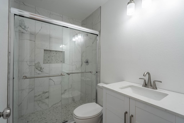 bathroom featuring a marble finish shower, toilet, and vanity