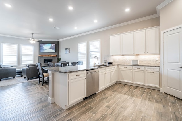 kitchen featuring white cabinets, dishwasher, a brick fireplace, and sink