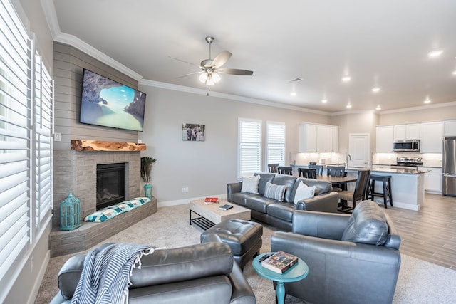 living room featuring ceiling fan, light hardwood / wood-style flooring, a brick fireplace, and ornamental molding