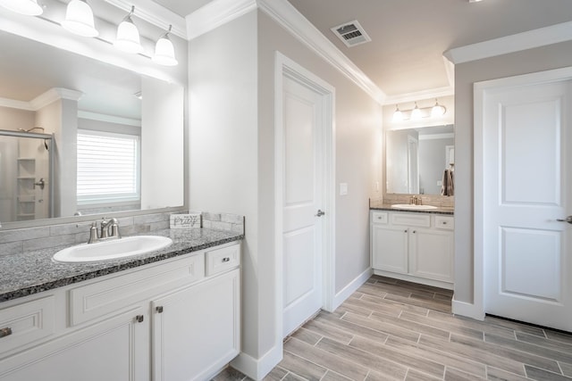 bathroom featuring a shower with door, ornamental molding, and vanity