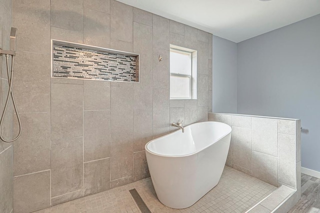 full bathroom with tiled shower, a freestanding tub, and visible vents