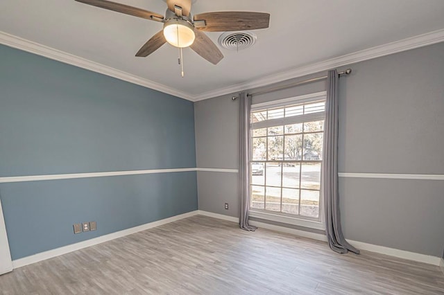 empty room with wood finished floors, a ceiling fan, visible vents, baseboards, and ornamental molding