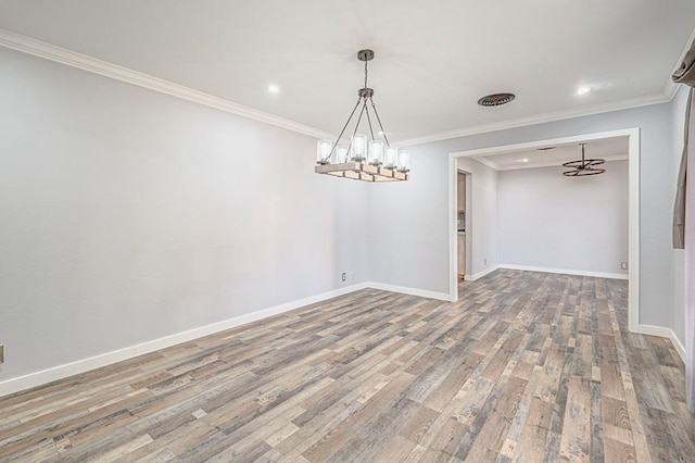 spare room with hardwood / wood-style flooring, ornamental molding, and a chandelier