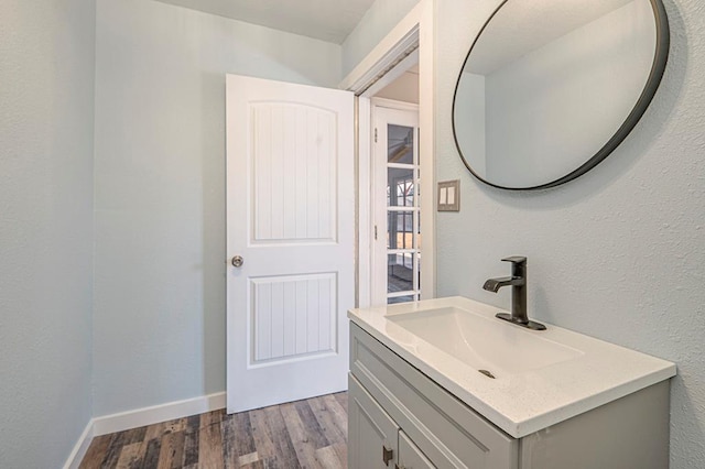 bathroom featuring baseboards, wood finished floors, and vanity