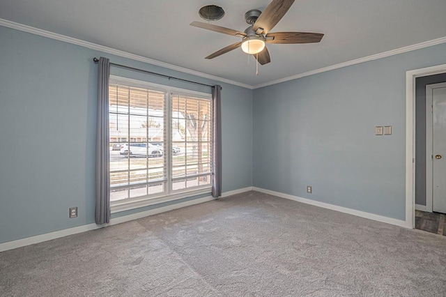 carpeted spare room featuring ornamental molding, baseboards, and a ceiling fan