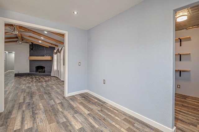 unfurnished living room with wood-type flooring, vaulted ceiling with beams, ceiling fan, and a fireplace