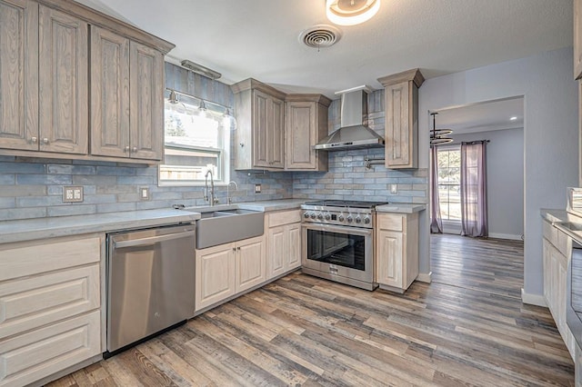 kitchen with dark wood-type flooring, sink, stainless steel appliances, decorative backsplash, and wall chimney range hood