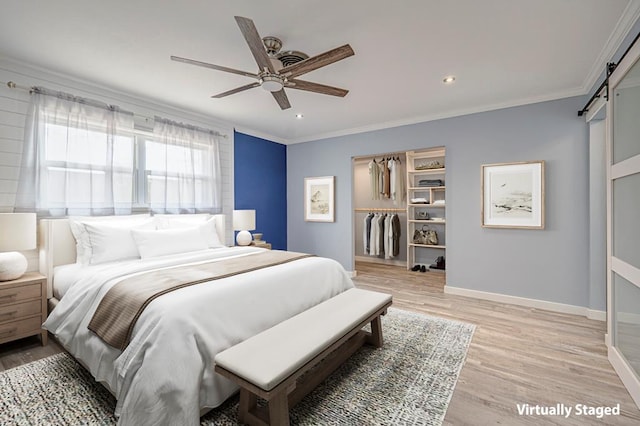 bedroom featuring light wood finished floors, recessed lighting, a barn door, ornamental molding, and baseboards