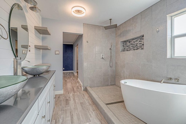 bathroom featuring tile walls, double vanity, a sink, wood finished floors, and walk in shower