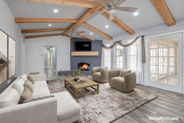 living area featuring plenty of natural light, ceiling fan, lofted ceiling with beams, and a fireplace