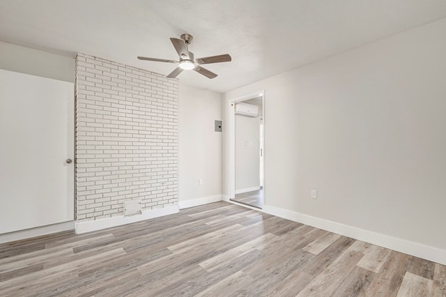 spare room featuring baseboards, a wall mounted air conditioner, a ceiling fan, and wood finished floors