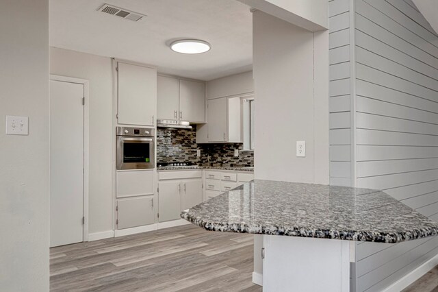 kitchen with visible vents, light wood finished floors, appliances with stainless steel finishes, and backsplash