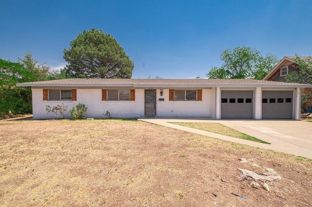 ranch-style house featuring concrete driveway, brick siding, a front lawn, and a garage