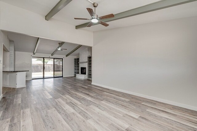 unfurnished living room with a ceiling fan, a brick fireplace, baseboards, lofted ceiling with beams, and light wood finished floors