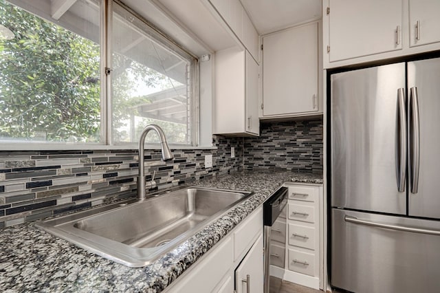 kitchen with backsplash, appliances with stainless steel finishes, a sink, white cabinets, and stone countertops